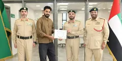 El expatriado junto a miembros de la polic&iacute;a tras devolver el dinero. (Dubai Police)