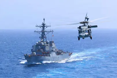 El USS Donald Cook transita por el mar Ar&aacute;bigo mientras un MH-60S Sea Hawk vuela cerca. (Centcom)