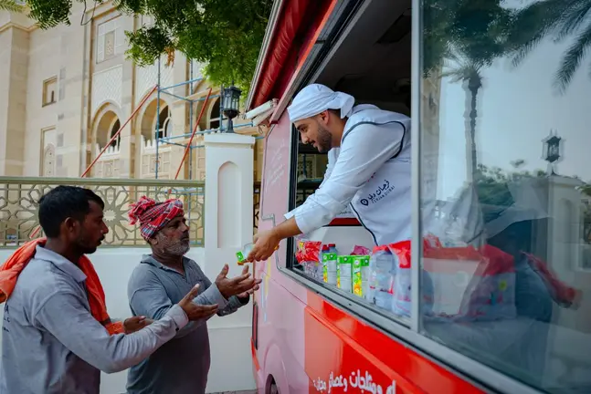 Un empleado entrega agua gratis a trabajadores en Emiratos. (X)