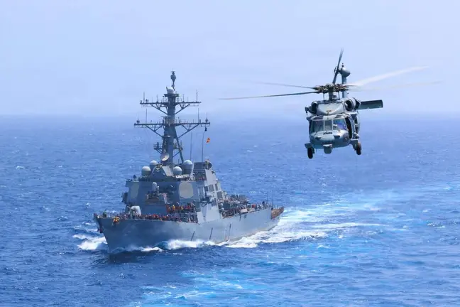 El USS Donald Cook transita por el mar Ar&aacute;bigo mientras un MH-60S Sea Hawk vuela cerca. (Centcom)