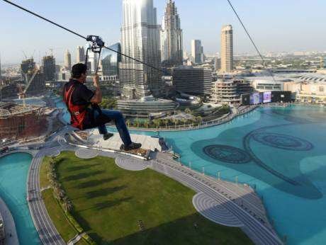 Un deportista se lanza en tirolina por la Fuente de Dubai.