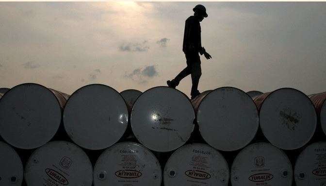 Un trabajador camina por barriles de petróleo.