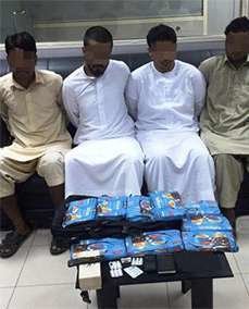 Los cuatro detenidos por tráfico de drogas en Abu Dhabi, junto al hachís confiscado.