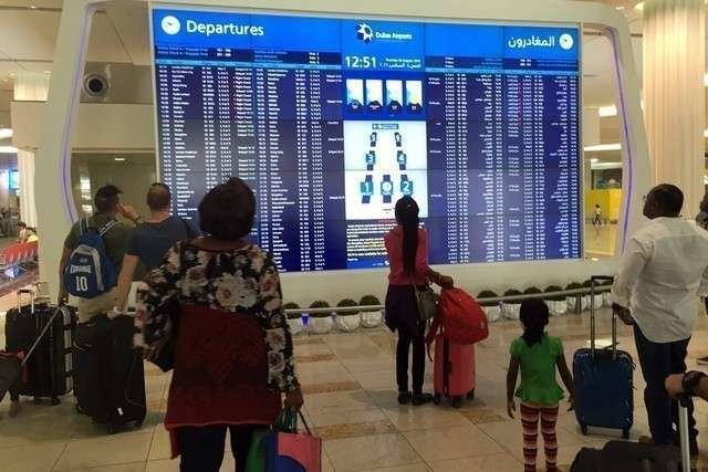Viajeros miran la pantalla de salidas en el Aeropuerto Internacional de Dubai. (AFP)