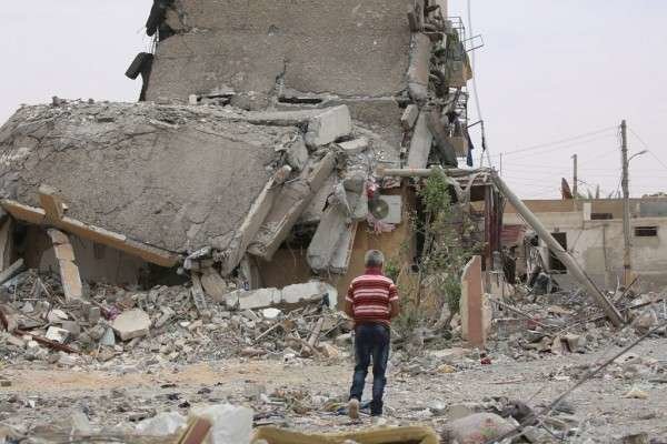 Una persona camina entre edificios destruidos y escombros en la ciudad de Tabqa, Raqqa, Siria. (UNICEF / Souleiman)