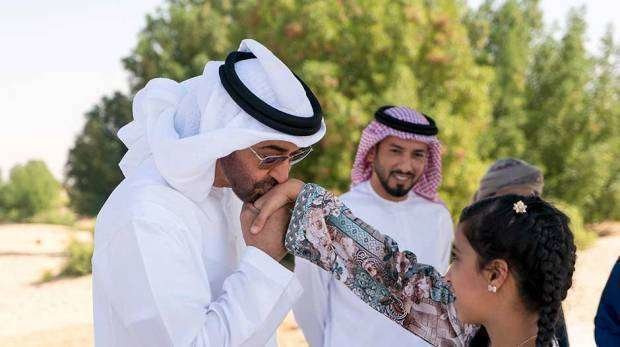 Sheikh Mohammed bin Zayed besa la mano de una de las niñas del Campamento Al Fakhr . (WAM)