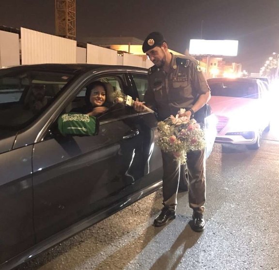 Un policía saudita entrega una rosa a una de las primeras mujeres conductoras tras el levantamiento de la prohibición. (@AboutHerOFCL)