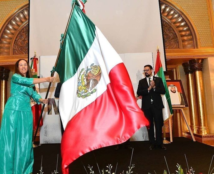La embajadora de México, Francisca Méndez, enarbola la bandera de México durante el Grito. (Manaf K. Abbas / EL CORREO)
