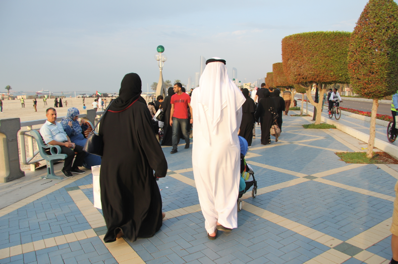 Una pareja de emiratíes camina por la Corniche de Abu Dhabi ataviada con las vestimentas tradicionales de Emiratos Árabes Unidos. (ELCORREO)