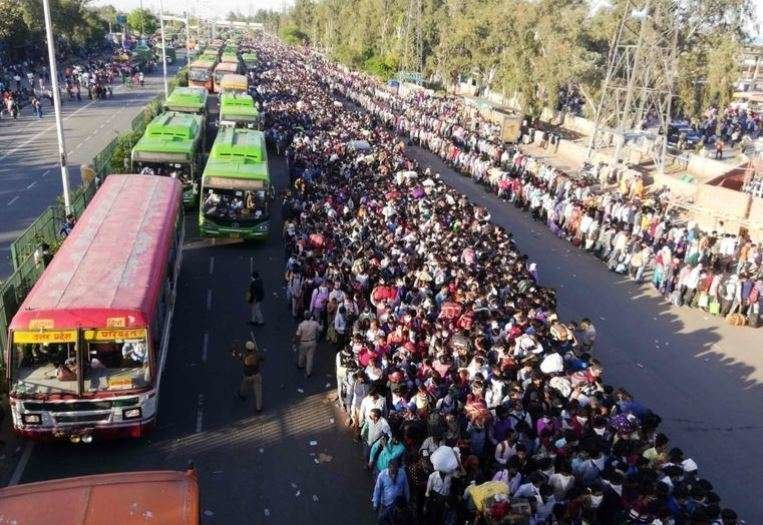 Trabajadores indios y sus familias intentan subirse a los autobuses en Nueva Delhi. (AFP)