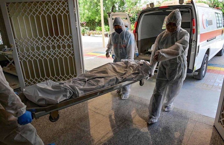  Empleados transportan el cuerpo de una víctima de Covid-19 para ser incinerado en el crematorio hindú New Sonapur en Dubai el 19 de abril de 2020. (AFP)