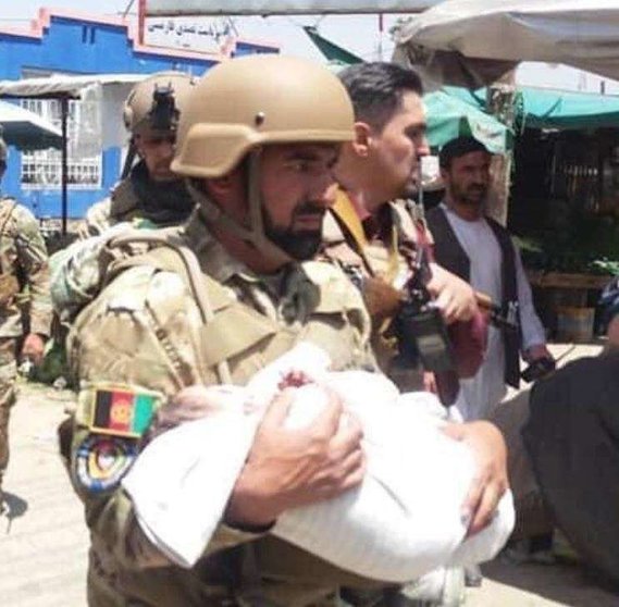 Un miembro de las Fuerzas de Seguridad en Kabul lleva en brazos a un recién nacido. (Twitter)