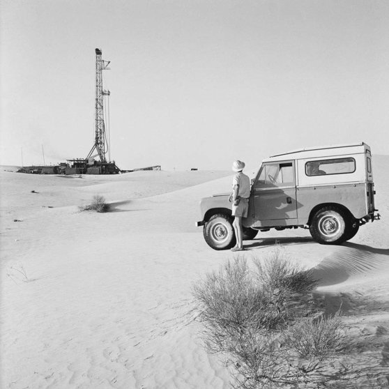 Un trabajador con su Land Rover observa una plataforma de perforación en el campo petrolero de Murban Bab en 1964. (The Naional)