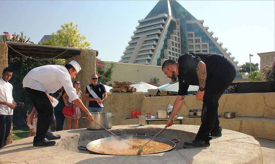 El chef del Seville's, Aleix Font -derecha-, prepara a leña en la terraza del restaurante una auténtica paella valenciana a leña. (EL CORREO)