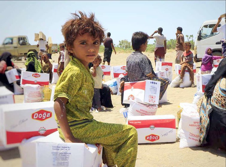 Un niño presencia la entrega de ayuda humanitaria en Yemen. (WAM)