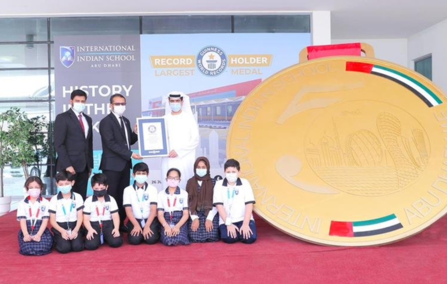 Estudiantes y profesores posan con la medalla de oro más grande del mundo. (Twitter)