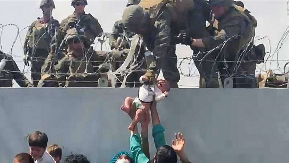 Momento en el que es entregado a los marines el bebé afgano por encima de la valla. (Twitter)