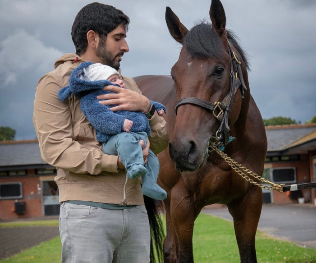 El jeque Hamdan con su hijo en brazos y el caballo campeón. (Twitter)