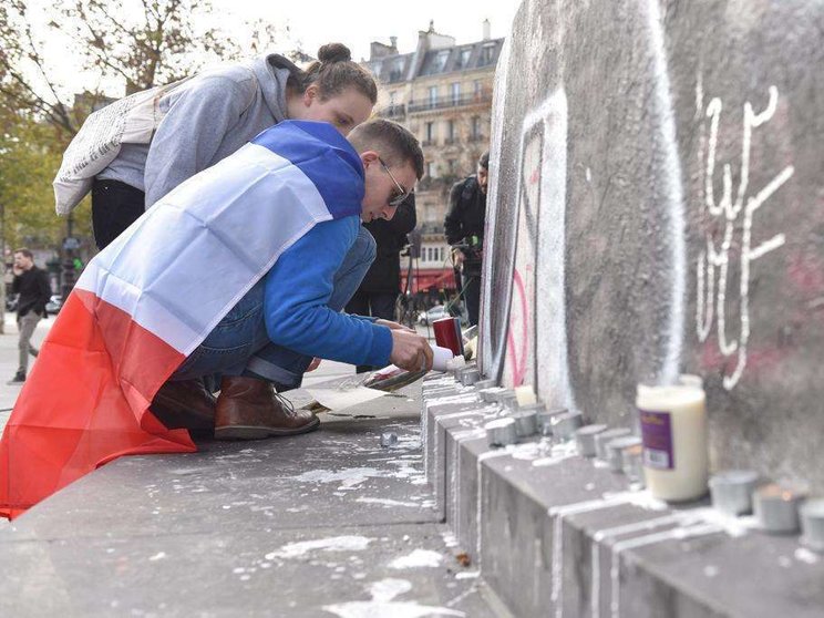 Unos jóvenes encienden velas en la Plaza de la República de Paris.