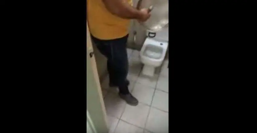 El trabajador friega un utensilio de la cocina en el baño.