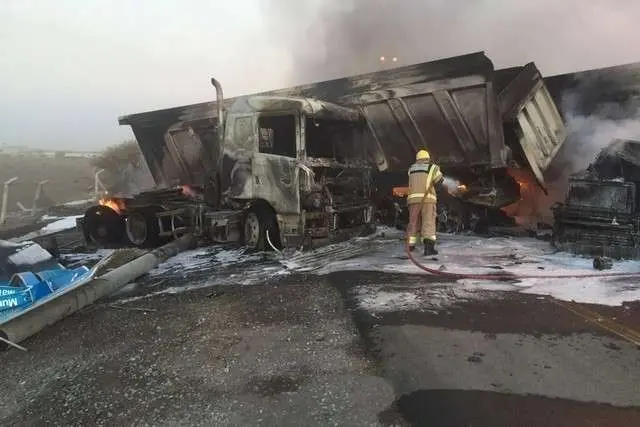 Un bombero apaga el fuego en los camiones siniestrados en Sharjah. (Policía de Sharjah)