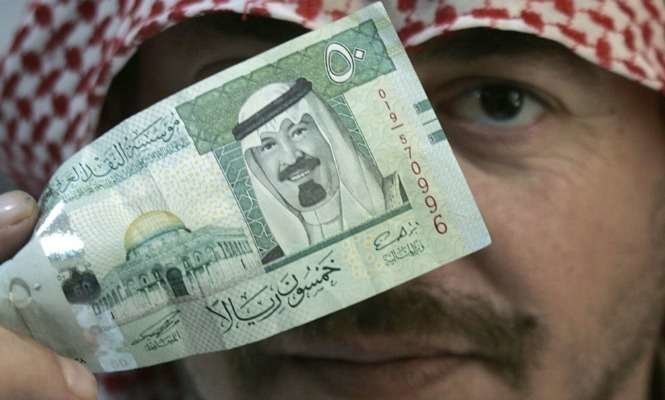 Un ciudadano saudí muestra un billete de curso legal en su país.
