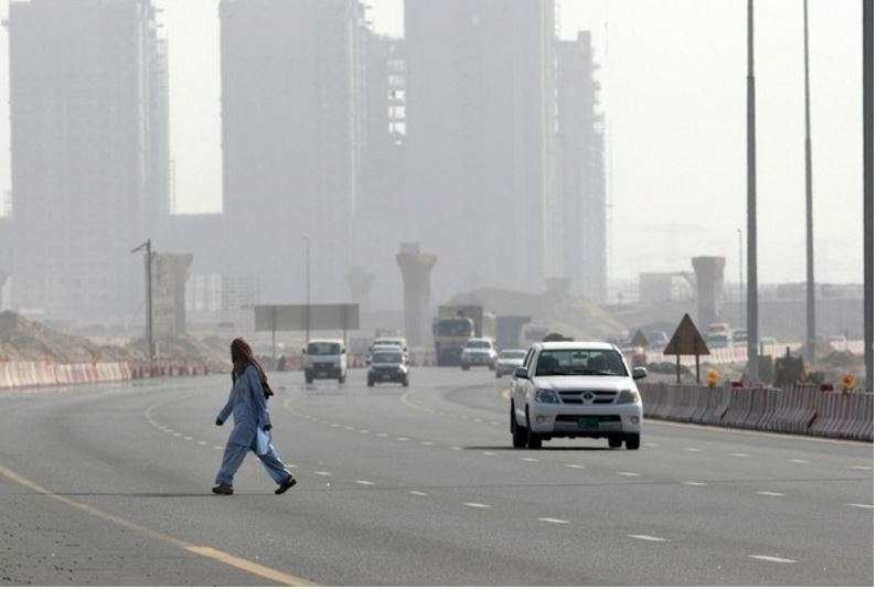 Un trabajador cruza una carretera en Dubai.