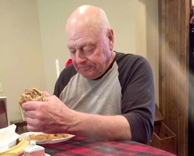 Abuelo come en solitario una hamburguesa.