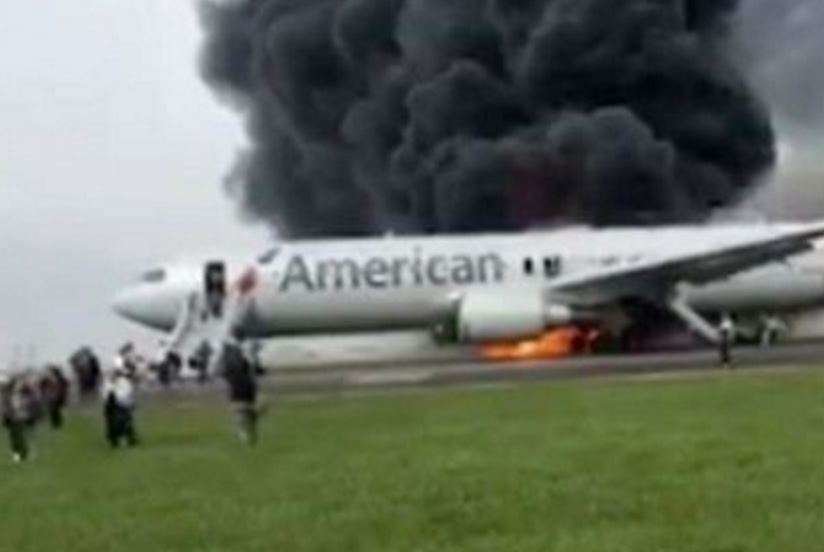 Pasajeros corren por la pista tras abandonar el avión en llamas de American Airlines. (Twittter)