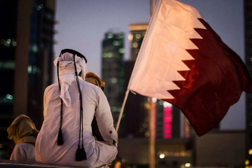 Un joven qatarí ante la bandera de su país.