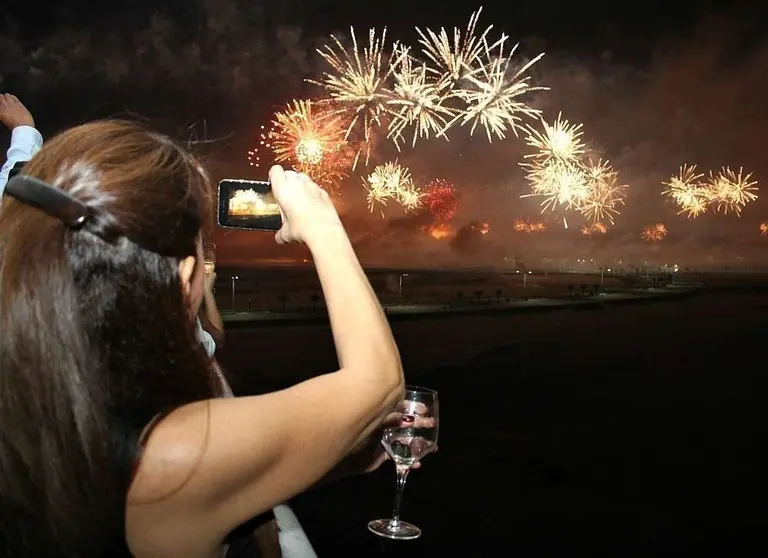 Residentes graban con sus celulares el espectáculo de fuegos artificiales en Ras Al Khaimah. (EL CORREO)