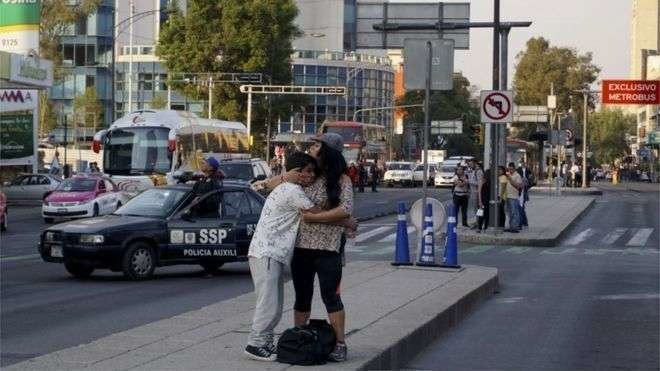 En la imagen de AFP, personas se abrazan en la calle, tras abandonar sus casas.