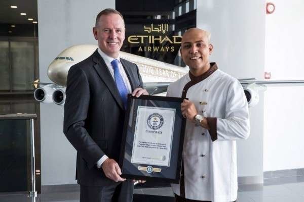 Tony Douglas, director ejecutivo de Etihad Aviation Group, y el chef Sanjay Thakur, muestran el reconocimiento. (WAM)