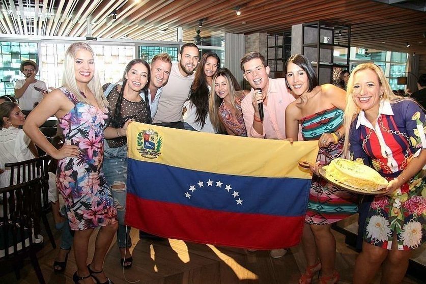 Grupo de asistentes junto a la bandera de Venezuela. (ELCORREO)