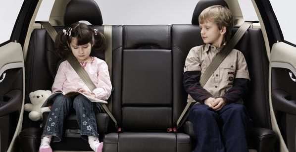 Menores sentados en el asiento trasero de un vehículo.