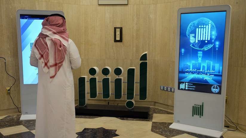 En la imagen de AFP, un empleado del Ministerio del Interior del Gobierno saudí frente al logo de la aplicación Absher. 