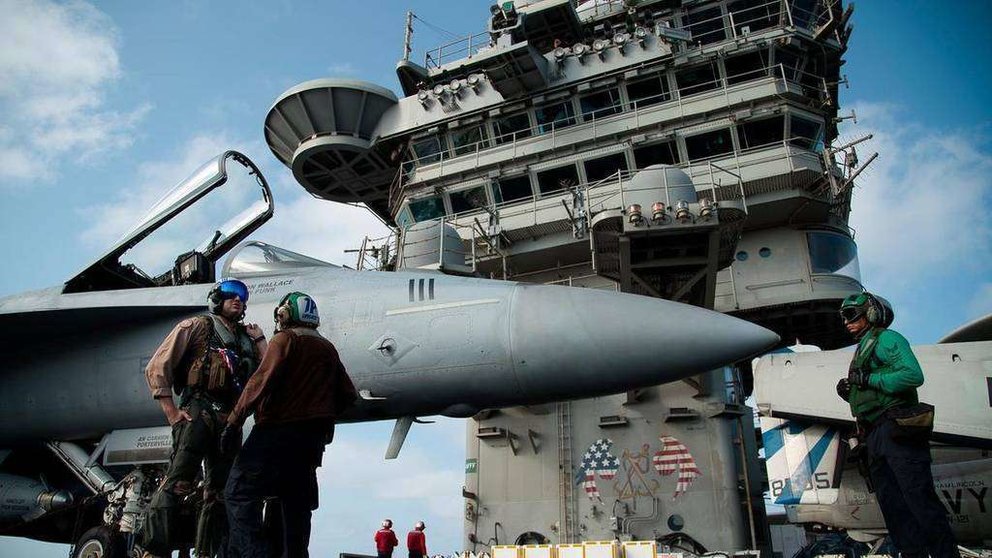 Un piloto habla a un miembro de la tripulación por un avión de combate F / A-18 en la cubierta del portaaviones USS Abraham Lincoln en el Mar Arábigo. (AP)
