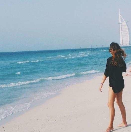 Una joven en una playa de Dubai con el Burj Al Arab al fondo. (EL CORREO)