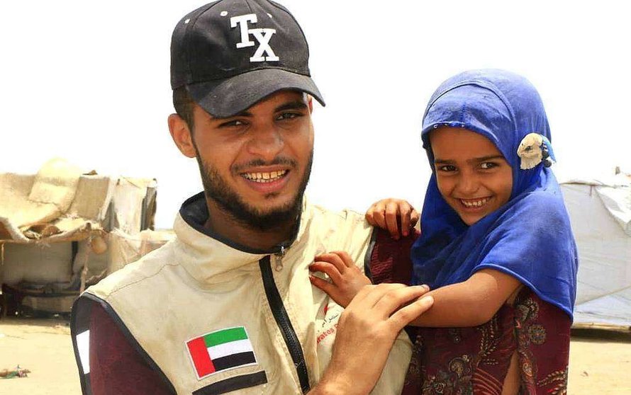 Emiratí con una niña receptora de la ayuda humanitaria que EAU proporciona al pueblo yemení. (WAM)