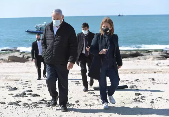 El primer ministro de Israel, Benjamin Netanyahu, y la ministra de Protección Medioambiental, Gila Gamliel, pasean por una playa afectada por los vertidos de petróleo.