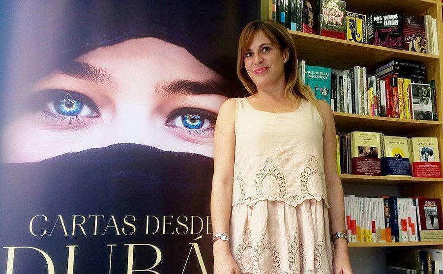 Asunta López, junto a una gran portada de su exitosa novela, 'Cartas desde Dubai'. (Cedida)