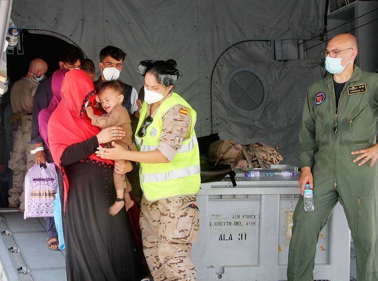 Militar española ayuda a una afgana y su hijo a descender del avión en la Base Aérea de Al Minhad en Dubai. (R. Pérez / EL CORREO)