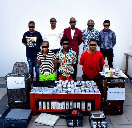 La banda detenida junto a los utensilios usados para falsificar los billetes. (Policía de Sharjah)