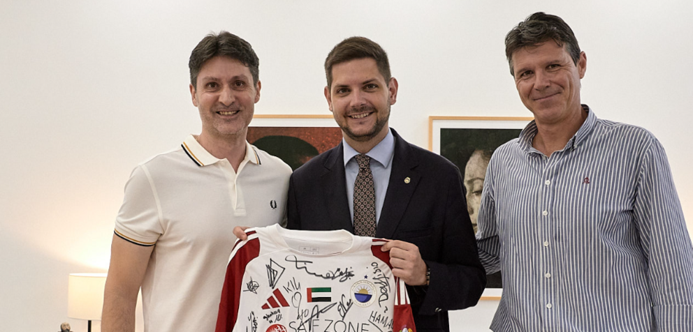 El alcalde de Gandía, en el centro de la imagen, recibe la camiseta del Sharjah. (X)