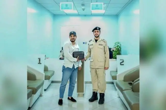 Un agente de la polic&iacute;a de Sharjah entrega la bolsa recuperada a su due&ntilde;o. (Polic&iacute;a de Sharjah)