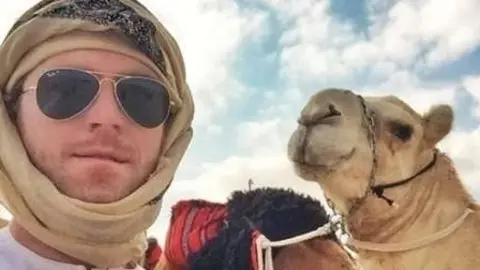 Max de Arabia junto a un camello en el desierto. 