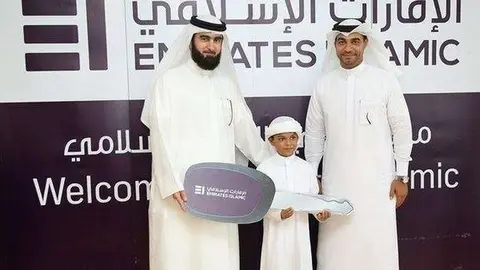 El afortunado ganador junto a su padre y el representante de la institución financiera.