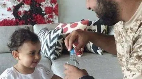 El jeque Theyab ofrece agua a una niña yemení.