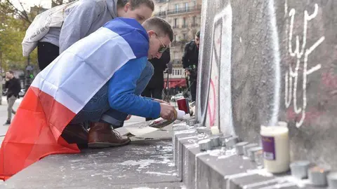 Unos jóvenes encienden velas en la Plaza de la República de Paris.
