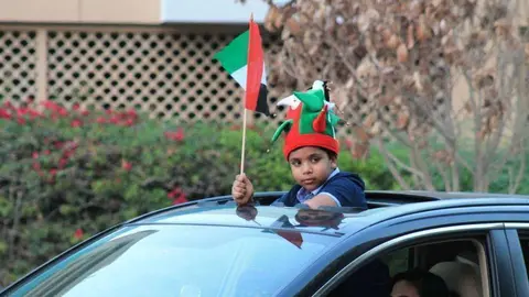 Un niño fuera del coche durante la celebración del Día Nacional de Emiratos. (EL CORREO)